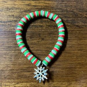 A Christmas clay beaded bracelet with a snowflake Charm.